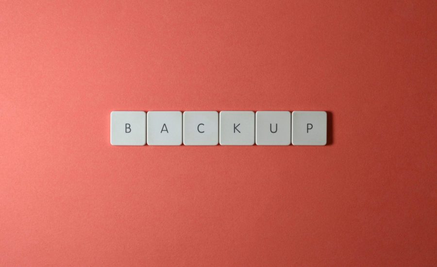 Free Close-up of keyboard keys spelling 'BACKUP' placed on a coral-colored surface. Stock Photo