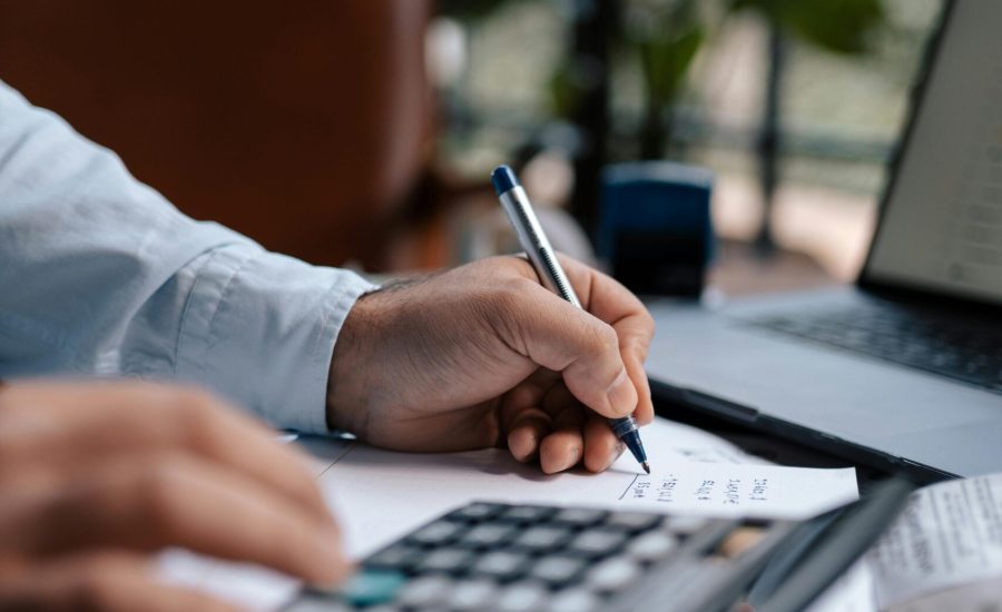 Free A person calculating finances with a calculator and pen on a desk indoors. Stock Photo